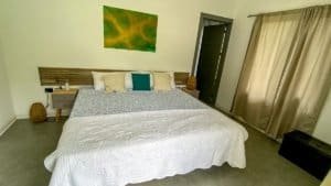 Comfortable bedroom with white bedding, colorful pillows, and natural light.