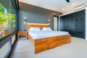 Contemporary bedroom with wooden bed, large window, and dark wardrobe in Costa Rica.