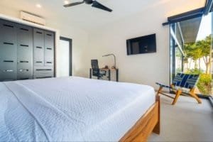 Bright bedroom with large window overlooking lush greenery and ocean in Dominical.