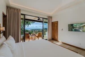 Spacious bedroom with balcony overlooking ocean and jungle in Costa Rica.