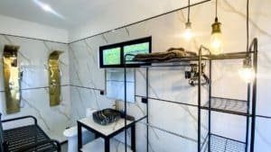 Contemporary bathroom with marble walls, black fixtures, and hanging lights.