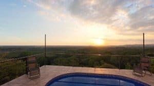 Sunset over lush landscape from a balcony with chairs in Dominical, Costa Rica.