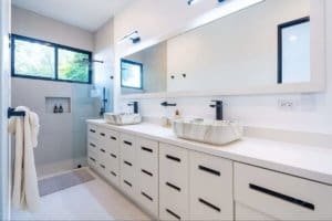 Modern bathroom with double vessel sinks, large mirror, and walk-in shower in Costa Rica.