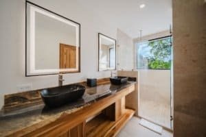 Modern bathroom with double vessel sinks, large mirror, and walk-in shower.