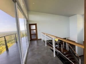 Bright interior with balcony overlooking lush landscape and ocean view.