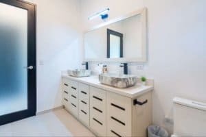 Modern bathroom with double stone sinks, large mirror, and minimalist decor.