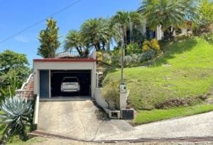 Gated community home with garage, lush greenery, and tropical plants in Dominical.