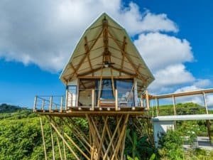 Treehouse with a boat-shaped roof overlooking lush greenery in Dominical, Costa Rica.