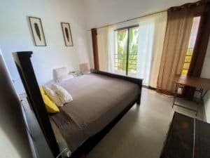 Bedroom with ocean view, balcony, and tropical surroundings in Dominical.