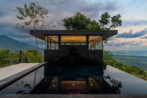 Modern home with infinity pool overlooking lush landscape and ocean view.