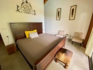 Comfortable bedroom with wooden bed, artwork, and seating area in Dominical.