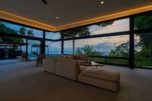Modern living room with large windows overlooking lush landscape and ocean.