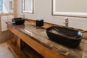 Modern bathroom with two black vessel sinks and a marble countertop.