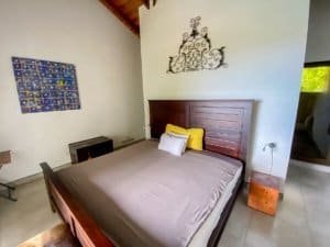 Bedroom with wooden headboard, decorative wall art, and ocean view in Dominical.