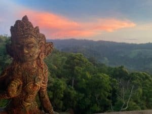Statue overlooking lush forest and sunset near Nauyaca Waterfalls.