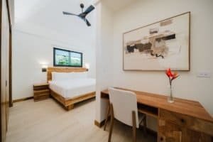 Bright bedroom with wooden furniture, desk, and abstract wall art in Costa Rica.