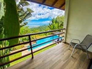 Balcony with ocean view, lush greenery, and pool in Dominical, Costa Rica.