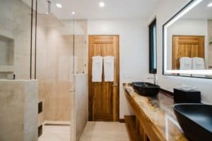 Modern bathroom with walk-in shower, double sink, and wooden accents.