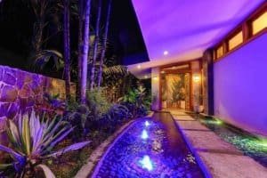 Elegant entrance to a mountain retreat with colorful lighting and lush garden.