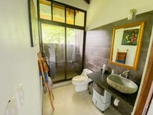 Bathroom with stone sink, toilet, and ocean view in Dominical property.