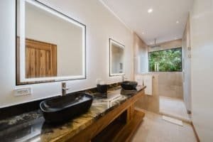 Modern bathroom with double black vessel sinks and walk-in shower.
