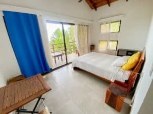 Bedroom with ocean view, balcony, and natural light in Dominical.