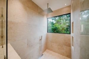 Modern shower with large window overlooking lush jungle in Costa Rica estate.