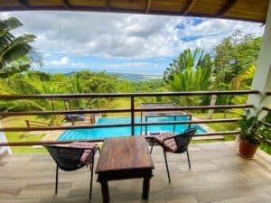 Balcony with seating overlooking lush tropical landscape and ocean view.