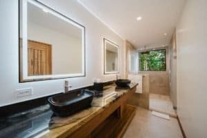 Modern bathroom with black sinks and jungle view window in Costa Rica.