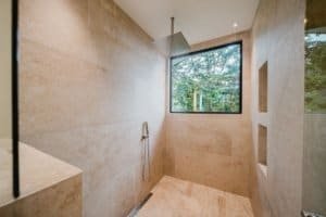 Luxurious shower with large window overlooking lush jungle in Costa Rica.