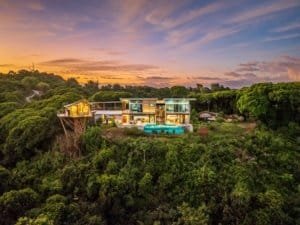 Modern luxury estate with infinity pool and hot tub overlooking lush mountains.