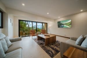Spacious living room with large windows overlooking lush jungle scenery.