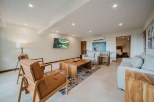 Spacious living room with ocean and jungle views, modern furniture, and bright lighting.
