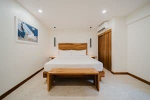 Minimalist bedroom with white walls, wooden bed frame, and closet in Costa Rica.