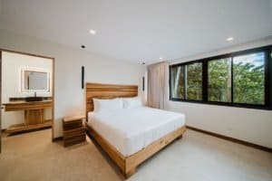 Modern bedroom with large window overlooking lush jungle in Costa Rica.