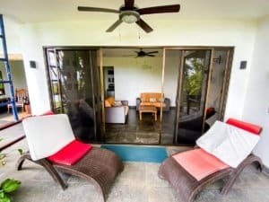 Balcony with lounge chairs overlooking a cozy living room with ocean view.
