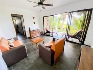Living room with ocean view, sliding glass doors, and tropical scenery.