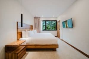 Spacious bedroom with large window overlooking lush jungle in Costa Rica.