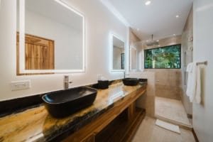 Modern bathroom with double mirrors, black vessel sinks, and walk-in shower.