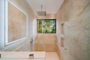 Modern bathroom with large window overlooking lush jungle scenery.