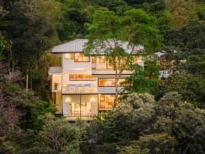 Modern multi-story house surrounded by lush green trees in Dominical.