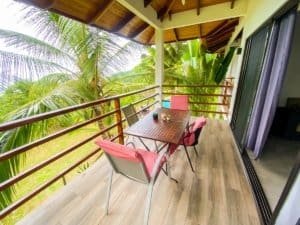 Balcony with outdoor table and chairs overlooking lush tropical trees in Dominical.