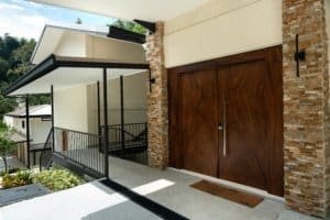 Modern Costa Rica estate entrance with wooden doors and stone accents.