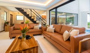 Spacious living room with leather sofas, wooden coffee table, and large windows.