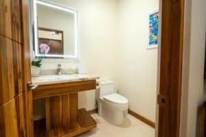 Modern bathroom with wooden accents, sink, and toilet in Costa Rica estate.