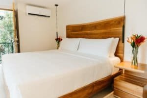 Modern bedroom with wooden headboard and mountain view from balcony.