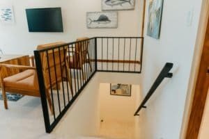 Modern staircase with black railing and artwork in a bright home interior.