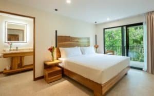 Modern bedroom with large window overlooking lush rainforest in Dominical.