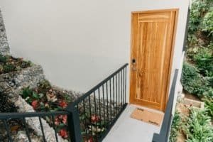 Wooden door with black railing and lush greenery in Dominical.