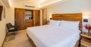 Elegant bedroom with king-size bed, wooden accents, and rainforest view.